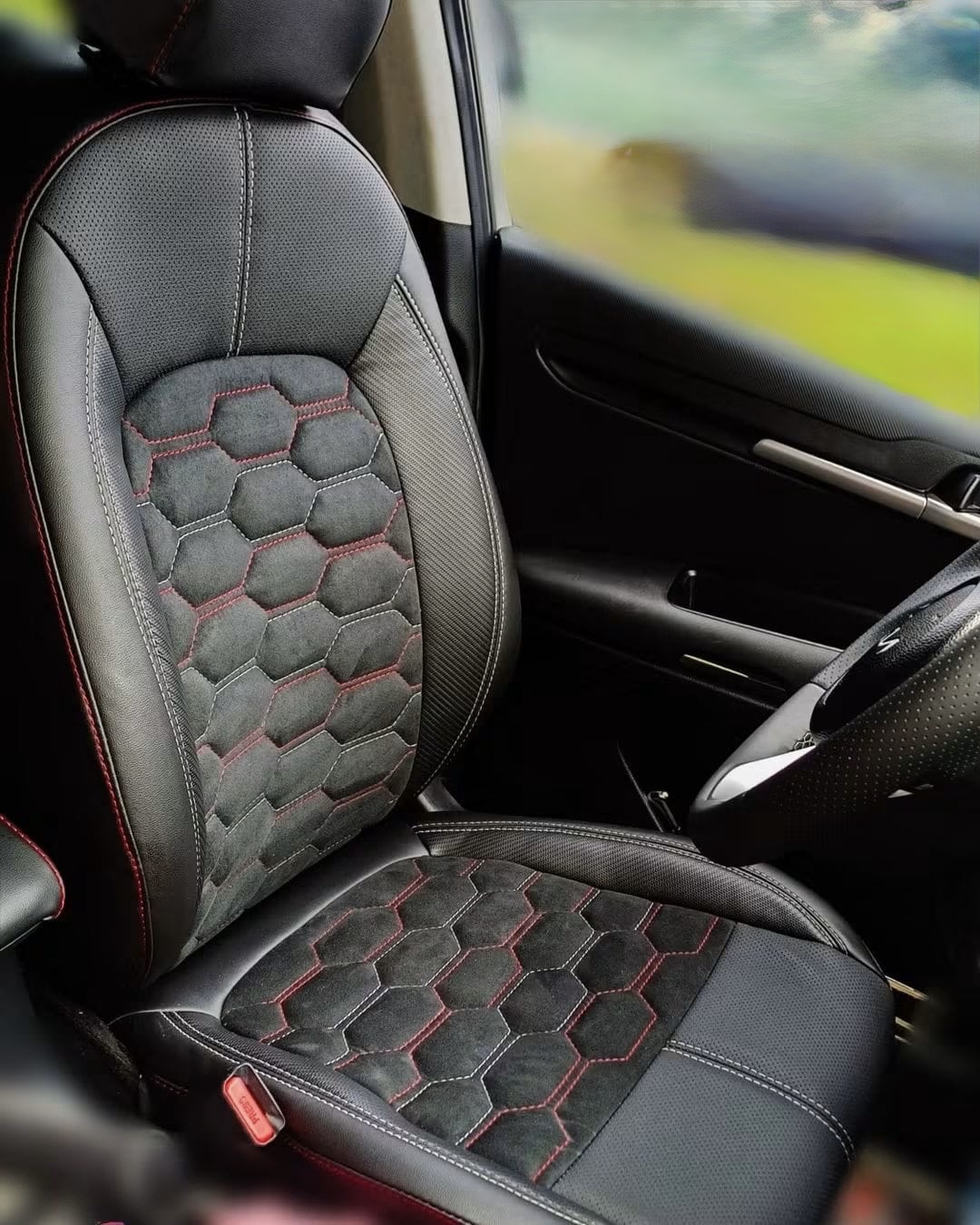 Asiento de coche tapizado en piel y alcántara con patrón hexagonal y costura roja
