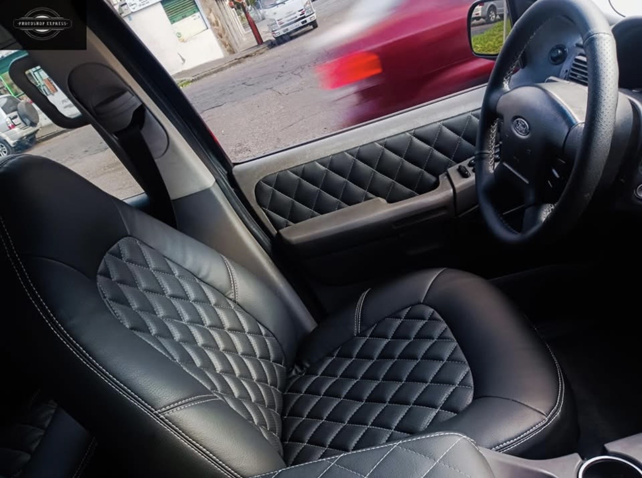 Interior de coche tapizado en piel negra con patrón de rombos y panel de puerta a juego